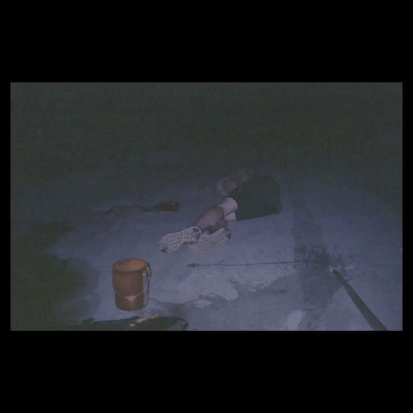 Dark, grainy image of a person lying on a concrete floor.