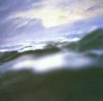 The image depicts a CD with a blurry, ocean-inspired cover art. Alt text: CD with ocean waves and cloudy sky on cover.