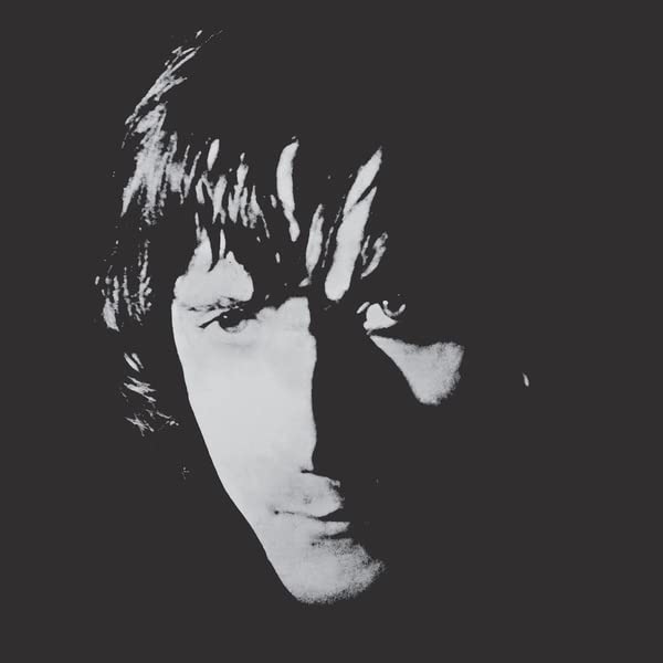 Black and white portrait of a man with long hair, partially in shadow.