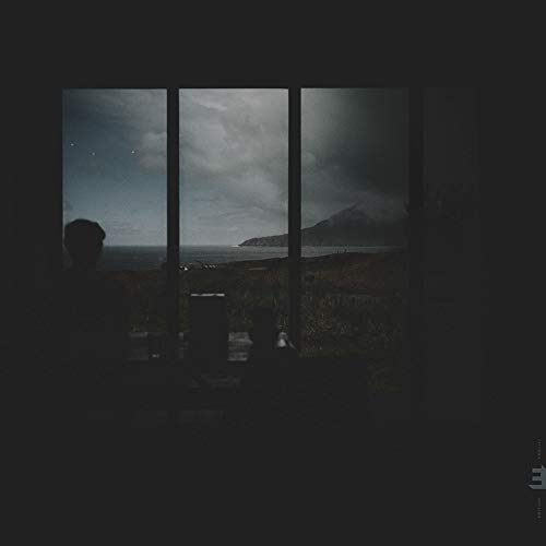 A darkened album cover with a silhouette and a cloudy landscape through a window.