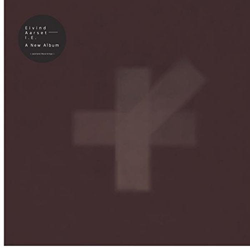 Brown album cover with a blurry white cross and text in the top-left corner.
