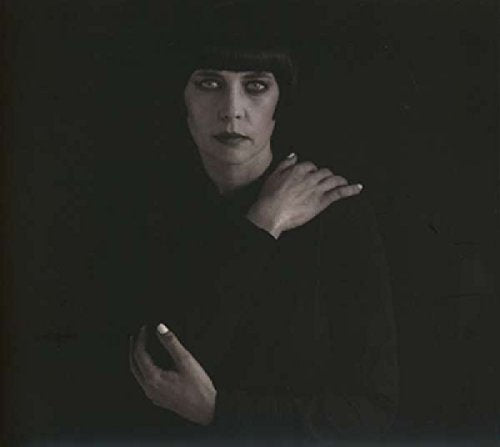 Black and white portrait of a woman in dark clothing against a dark background.