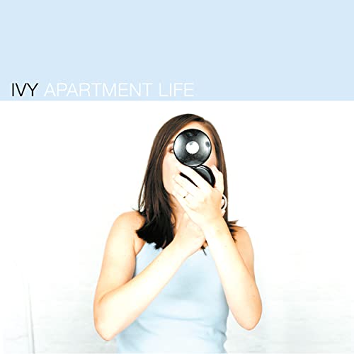 Woman holding a vintage camera to her face, album cover.