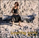 CD cover: Susi Hyldgaard sits on driftwood on a rocky beach.
