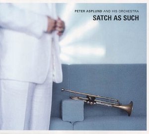 A man in white stands beside a blue sofa with a trumpet on it.