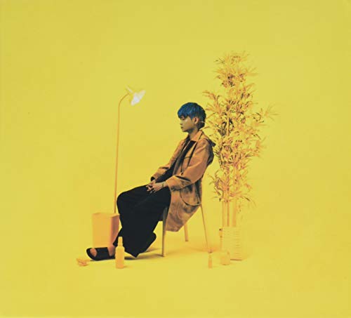 Man in brown coat sits under a lamp with bamboo plants.