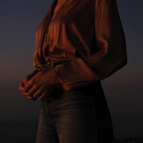 Close-up of a person in jeans and a shirt, warmly lit.