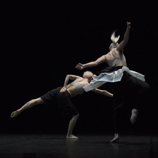 Two dancers in contemporary poses against a dark background.