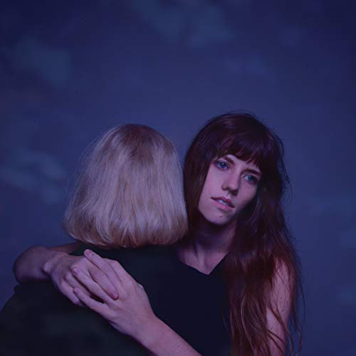 "Two women embracing, one with long dark hair, against a dark blue background."