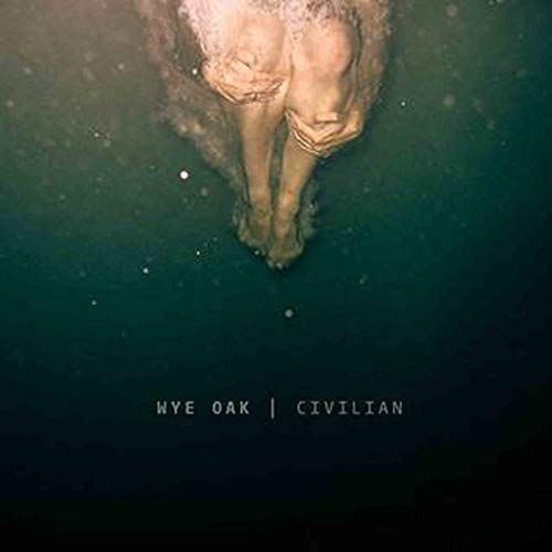 Submerged person with legs drawn up, dark teal water, album cover.