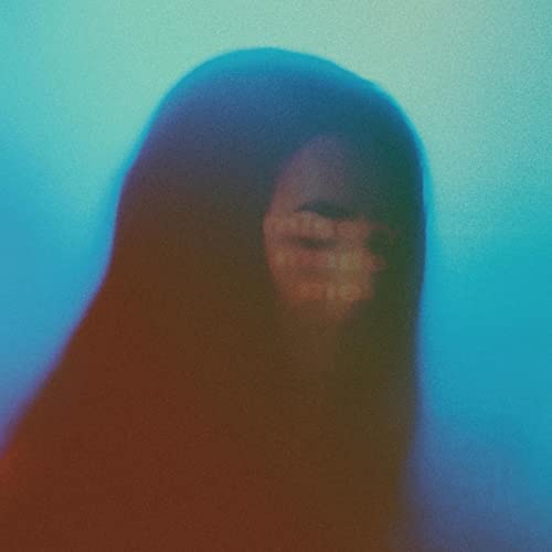 Blurred face with tear-like markings against a blue and orange background.