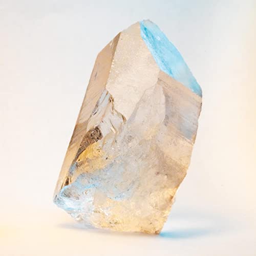 Clear quartz crystal with blue tint, angled against a white background.