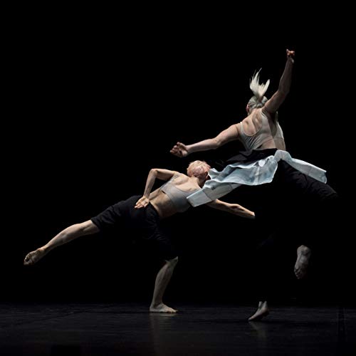Two dancers in motion, mid-air, against a dark background.