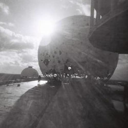 Black and white landscape with a large, spherical structure and a lone figure.