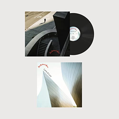 Vinyl record with album cover featuring architectural photography and a lone figure.