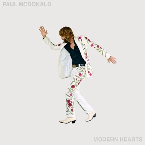Paul McDonald in a floral suit, posing dynamically against a pale background.