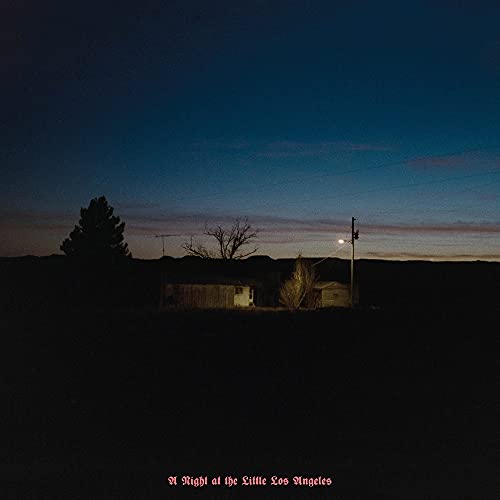 Dark landscape with silhouetted buildings and power lines under a twilight sky.