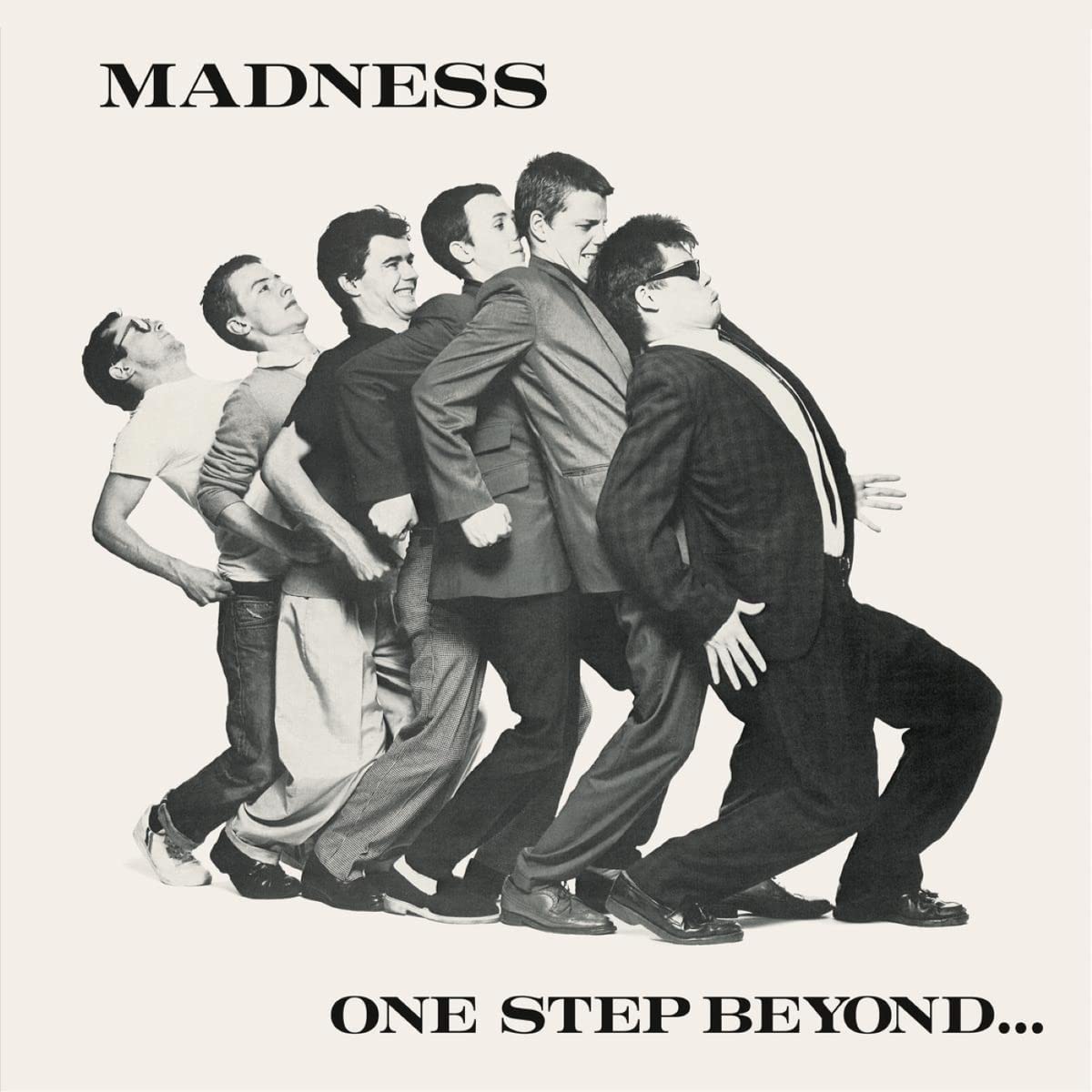 Black and white album cover featuring Madness band members in suits leaning forward.