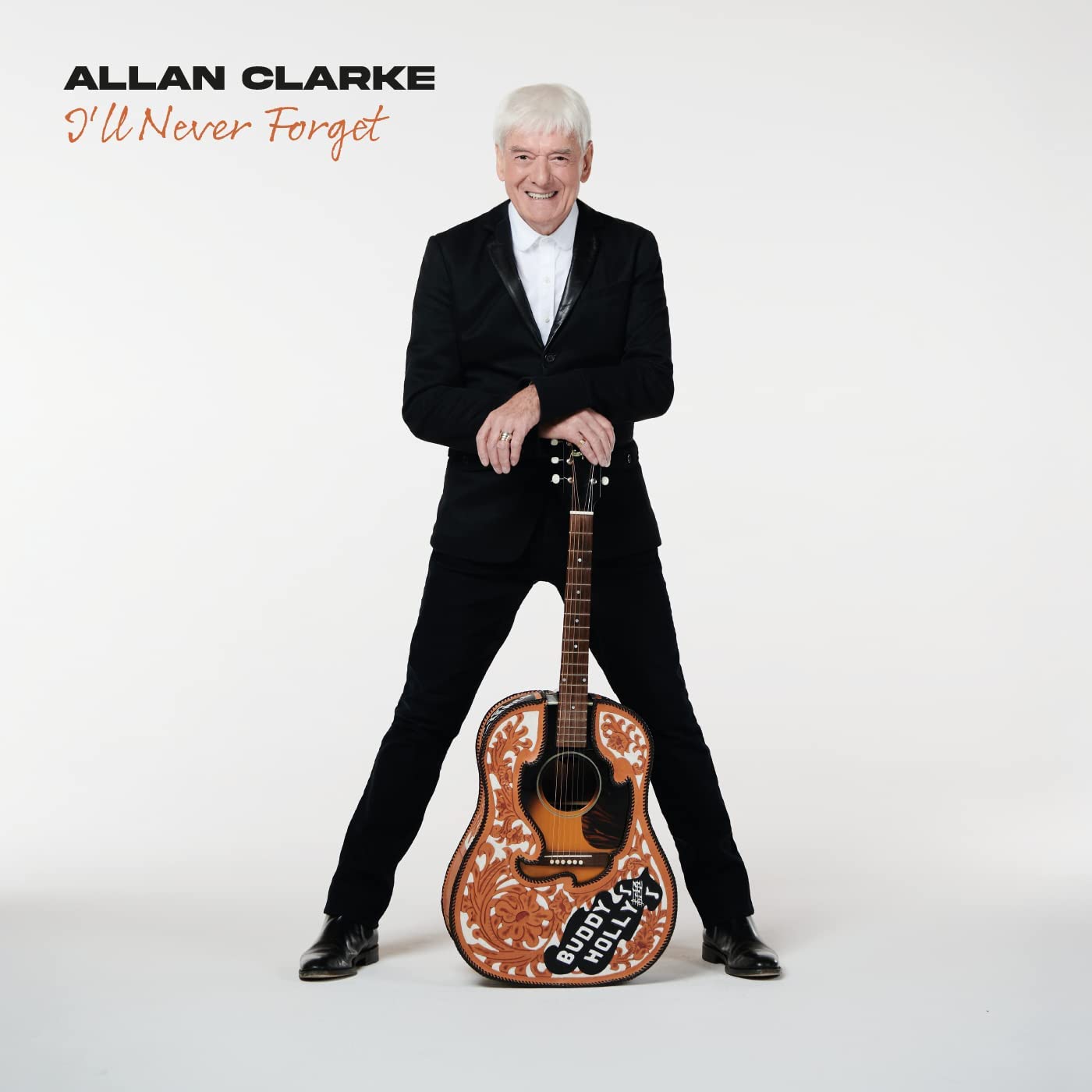 Man in black suit holding a decorated guitar, white background, album cover artwork.