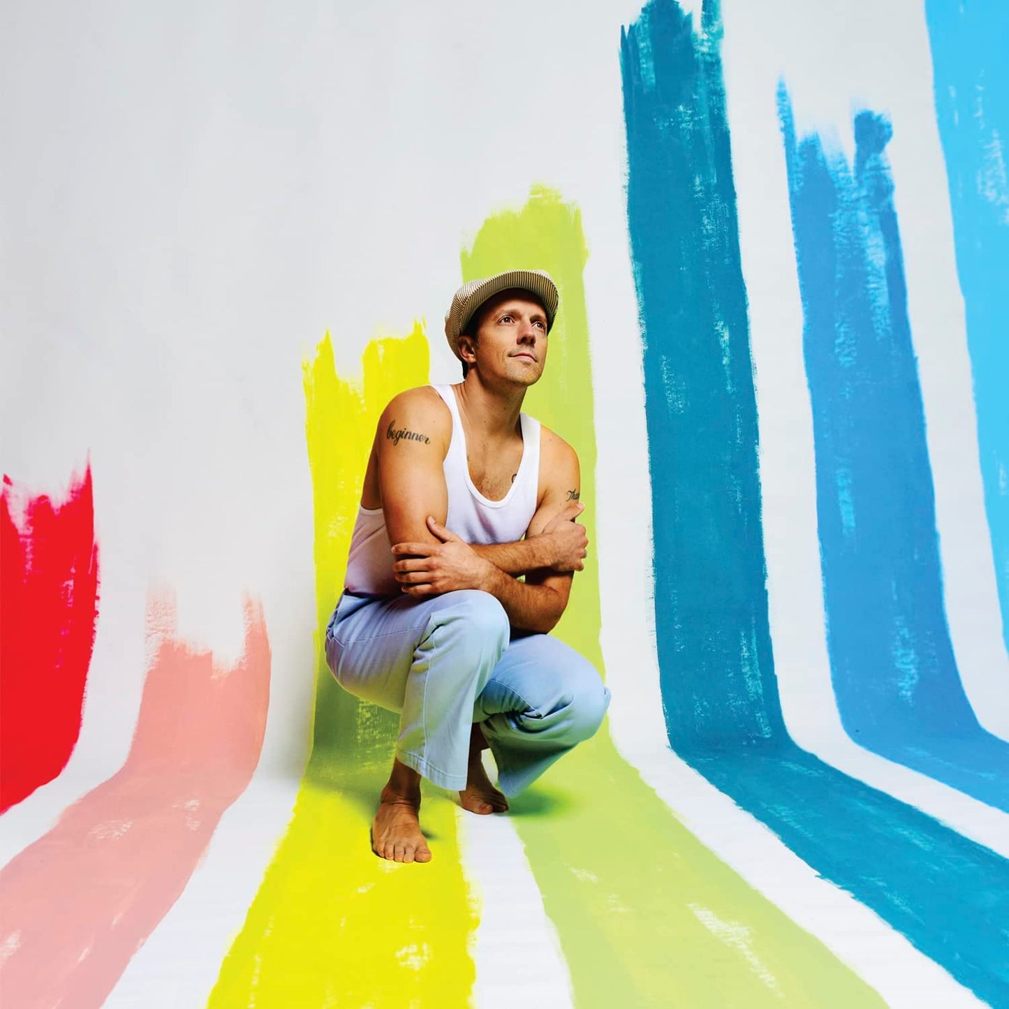Jason Mraz portrait with colorful painted stripes in the background.