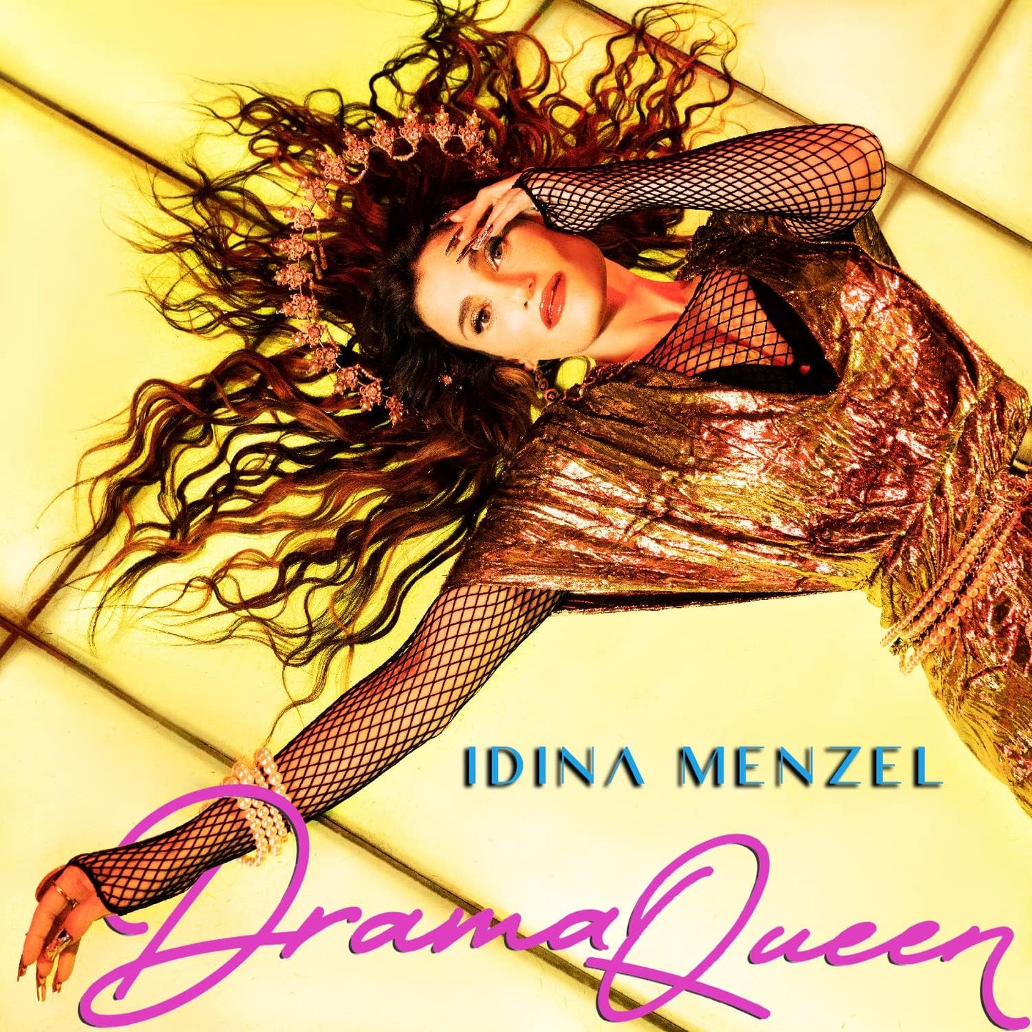 Idina Menzel lying on a yellow couch, wearing a shiny dress and fishnet sleeves.