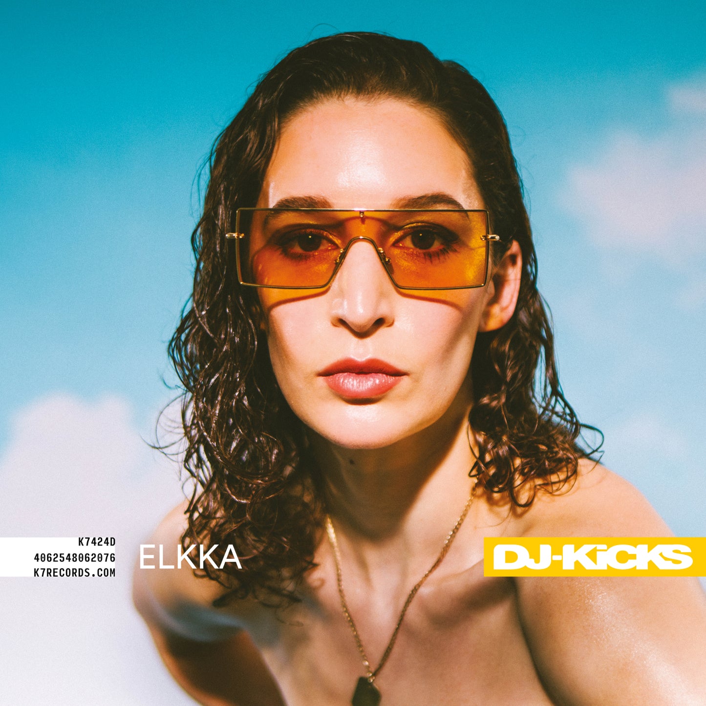Close-up portrait of Elkka wearing orange-tinted sunglasses, album cover art.