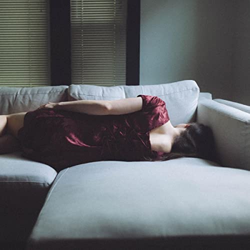 Woman in red dress lying on a gray couch.