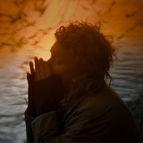 Silhouetted person with curly hair against an orange and blue sky.