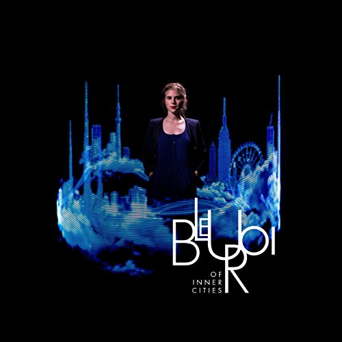 Woman in front of a blue, abstract cityscape with album title “Bleu Roi”.