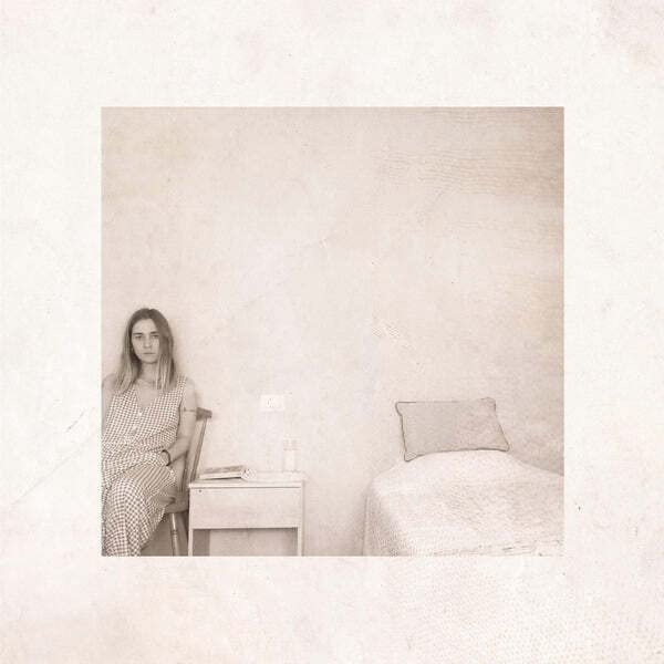 Woman sitting in a sparsely furnished room, album cover art.