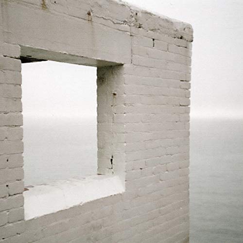 White brick structure with a rectangular opening overlooking a hazy sea.