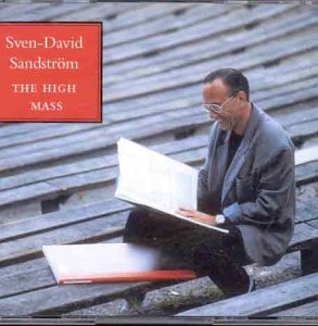 Man sits on wooden slats, reading sheet music, wearing glasses and a gray jacket.