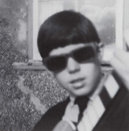 The alt text for the image is: "Black and white photo of a man wearing sunglasses."