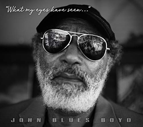 Black and white album cover featuring a man with sunglasses and a hat.