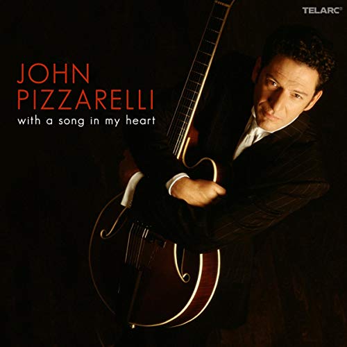 John Pizzarelli holding a guitar on the album cover, dark background.