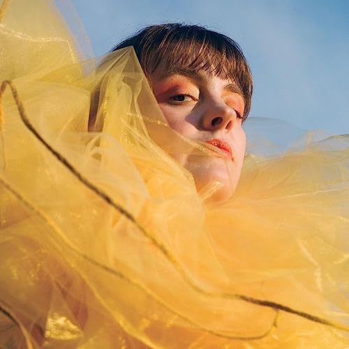 Woman with short hair, partially obscured by yellow fabric.