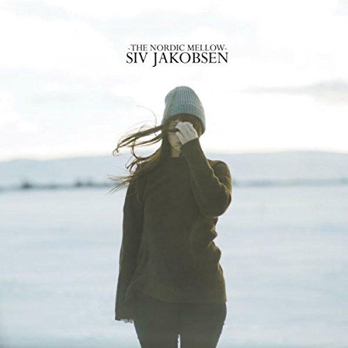Woman wearing a beanie, standing outdoors with wind blowing through her hair.