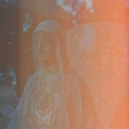 Blurred portrait of a person with long hair, orange and white tones.