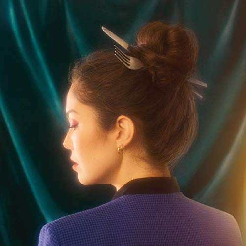 The alt text for the image is: "Woman with brown hair in a bun, wearing a purple jacket."