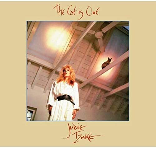 Judie Tzuke's album cover: woman in white robe, black cat on ceiling, beige background.