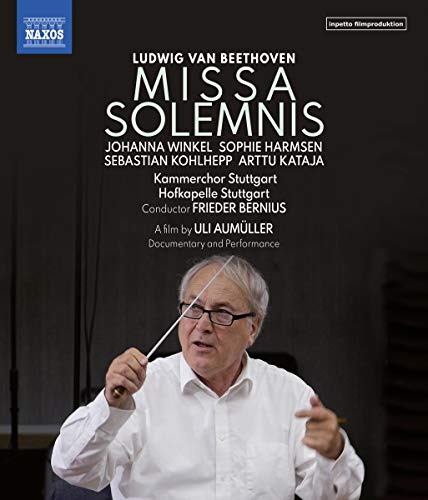 Conductor Frieder Bernius holds a baton, wearing glasses and a white shirt.