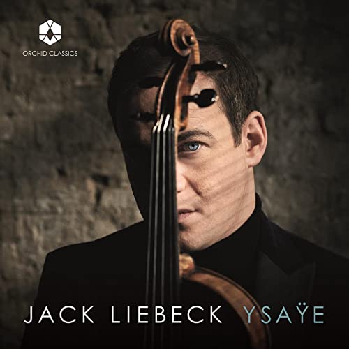 Close-up of violinist Jack Liebeck with his instrument against a stone wall.