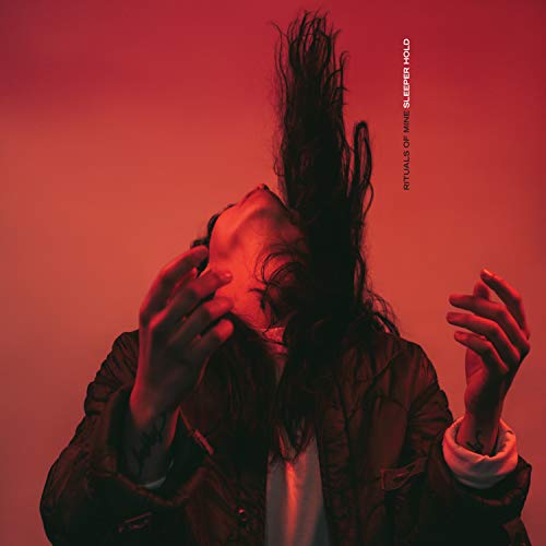 Person with obscured face and messy hair against a red background.