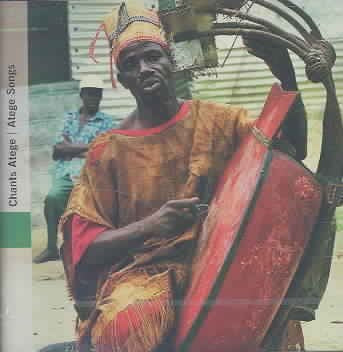 Man in traditional yellow and red attire playing a large red drum.