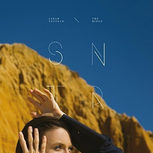 Vinyl album cover featuring a woman with her hands on her head, against a rocky cliff.