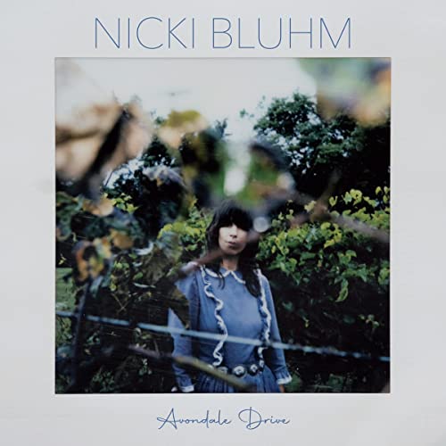 Album cover for Nicki Bluhm’s “Avondale Drive” featuring a woman in nature.