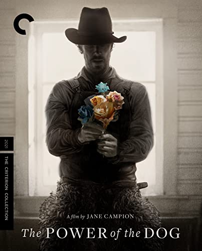 Man in hat and workwear holds flowers, film "The Power of the Dog".