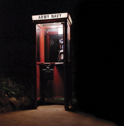 "Red phone booth with 'Army Navy' sign, illuminated in a dark setting."