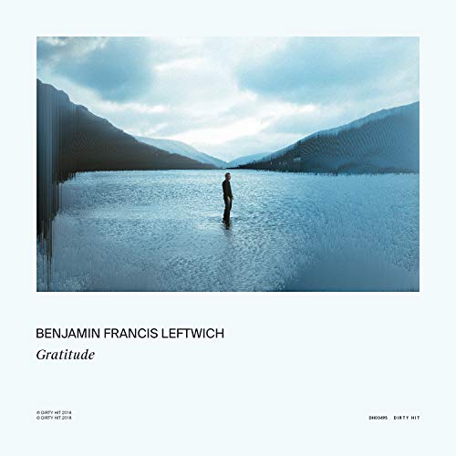"Album cover with a man standing in a frozen lake surrounded by mountains."