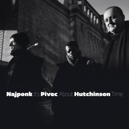 Black and white album cover with three men standing in front of a building.